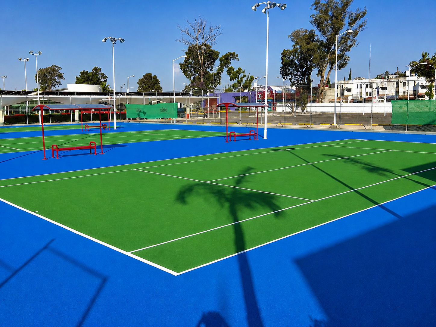 Complejo de canchas deportivas en azul y verde con luminarias y equipamiento